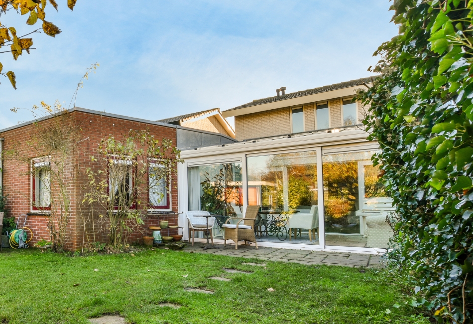 Vue sur l'extérieur d'une maison avec le jardin et une véranda aménagée